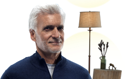 Man in front of a lamp and table.